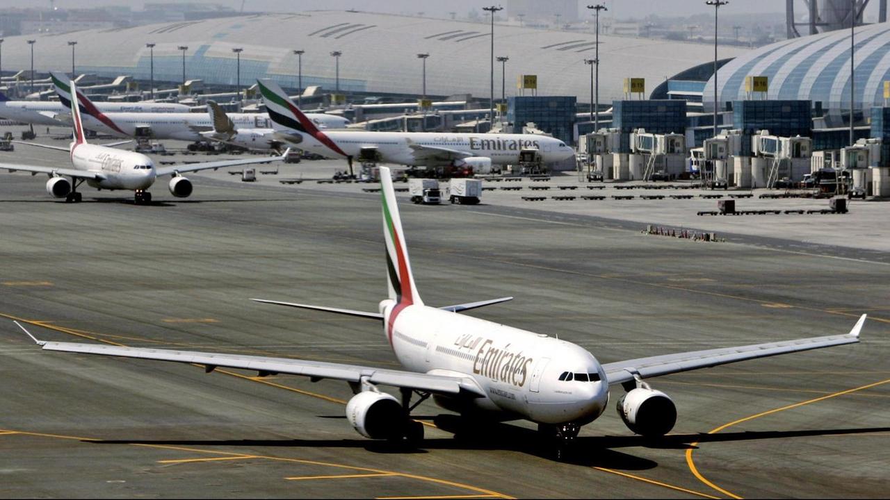 Flughafen Dubai mit mehreren Flugzeugen der Linie Emirates vor dem Hauptgebäude.