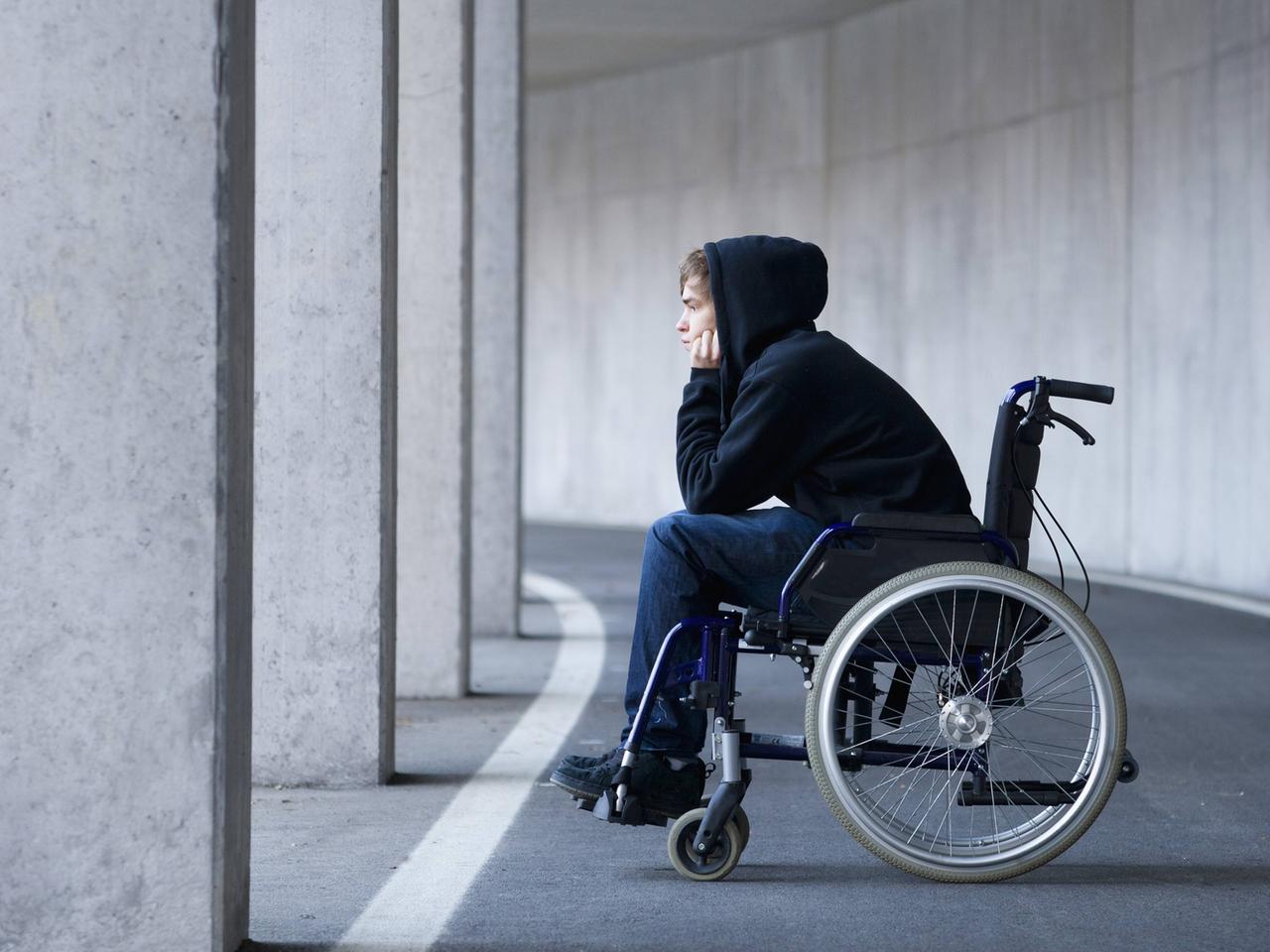Ein junger Mann sitzt in einem Rollstuhl.