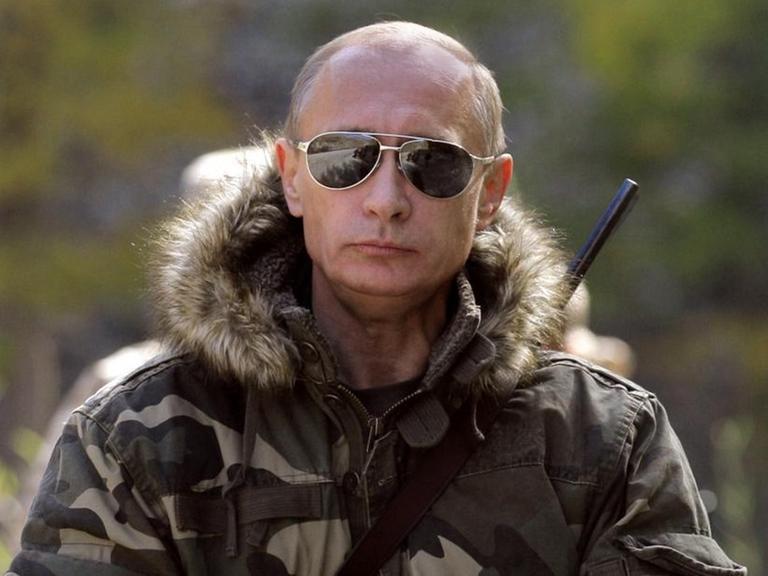 Wladimir Putin mit Gewehr über der Schulter auf einem Pferd sitzend.