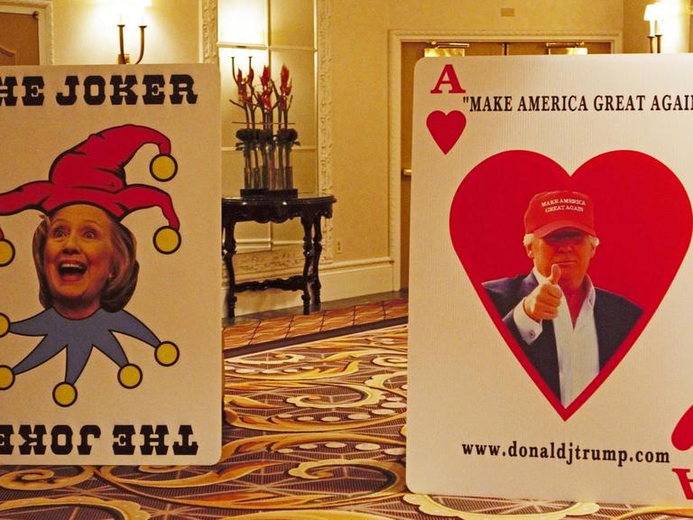 Die Köpfe der beiden Politiker sind auf zwei überdimensionierten Spielkarten in einem Flur dargestellt.