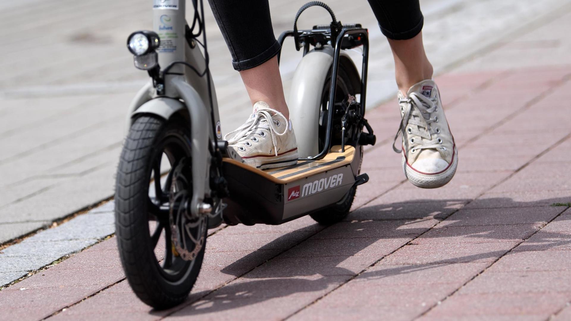 Die Füße einer Frau auf einem E-Scooter.