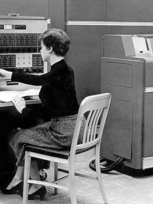 Schwarzweißaufnahme einer Frau, die 1954 in New York vor dem Computer IBM 650 sitzt.