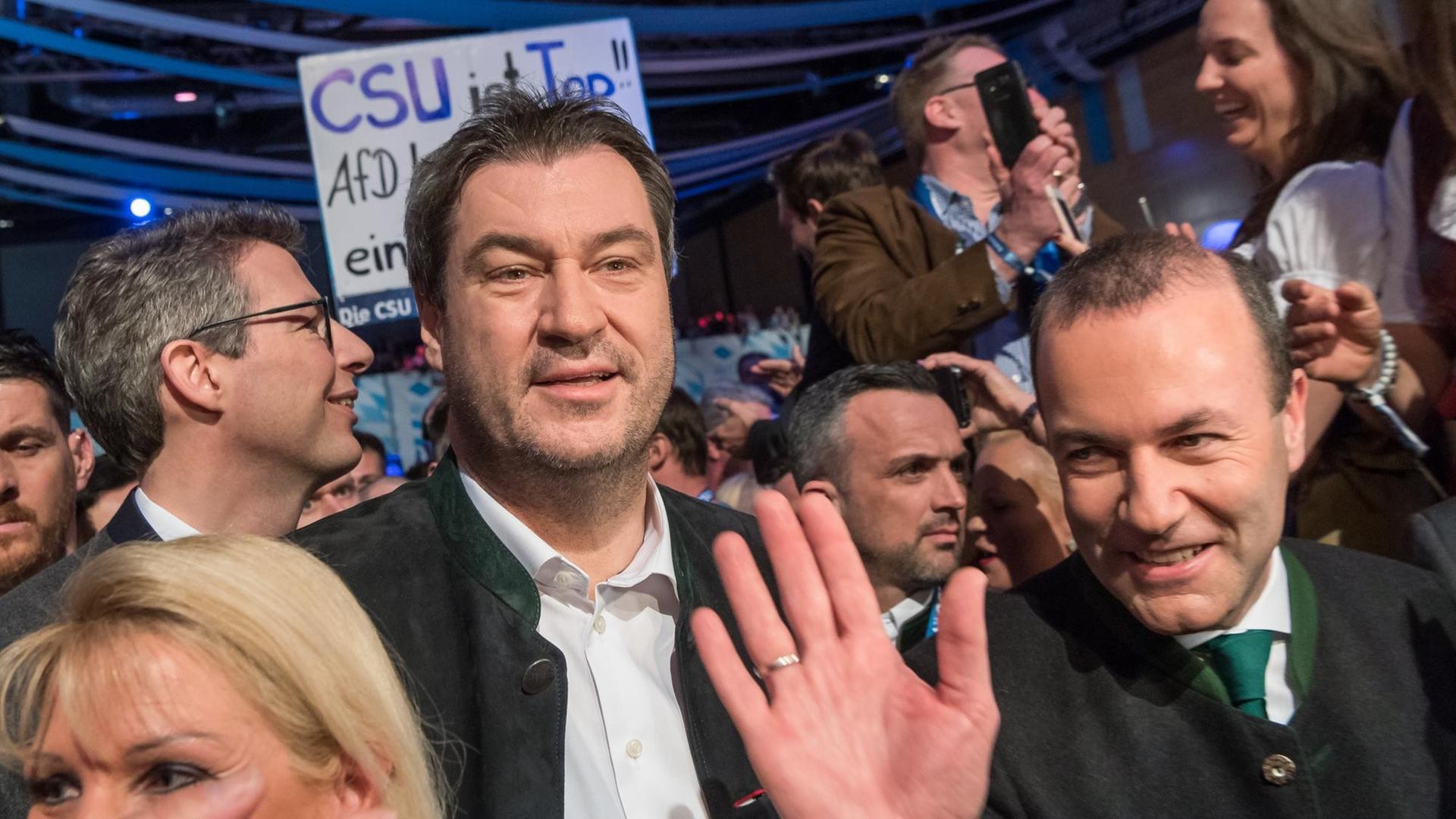 Manfred Weber (r) und Markus Söder drängen sich durch die Menschenmenge. Weber winkt mit der rechten Hand.