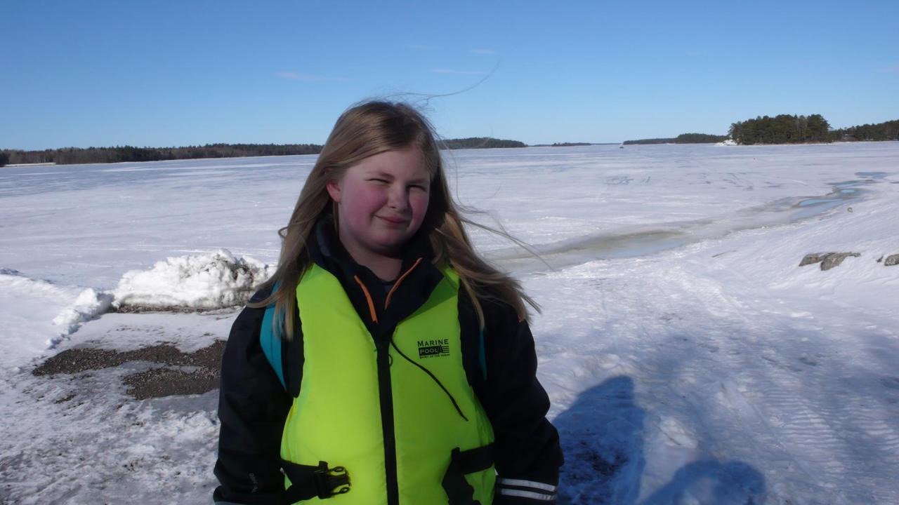 Ein 12jähriges Mädchen steht in einer Schneelandschaft und schaut in die Kamera