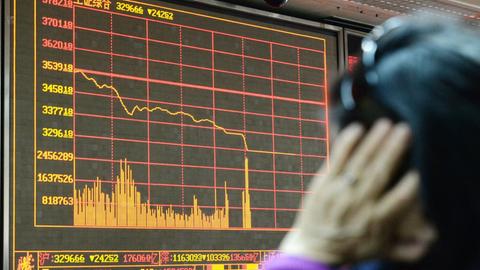 Ein Händler blickt auf eine elektronische Anzeigetafel. Der Aktienhandel in China wurde für den Rest des Tages wegen der fallenden Kurse gestoppt.