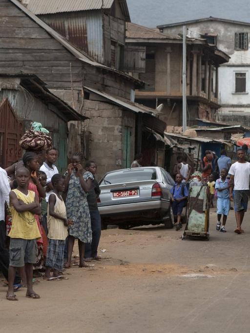 Straßenszene in der Hauptstadt Freetown in Sierra Leone - Kinder, Erwachsene, Autos und einfache Häuser, aufgenommen am 09.03.2011.