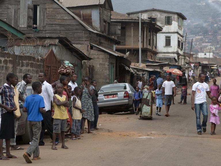 Straßenszene in der Hauptstadt Freetown in Sierra Leone - Kinder, Erwachsene, Autos und einfache Häuser, aufgenommen am 09.03.2011.