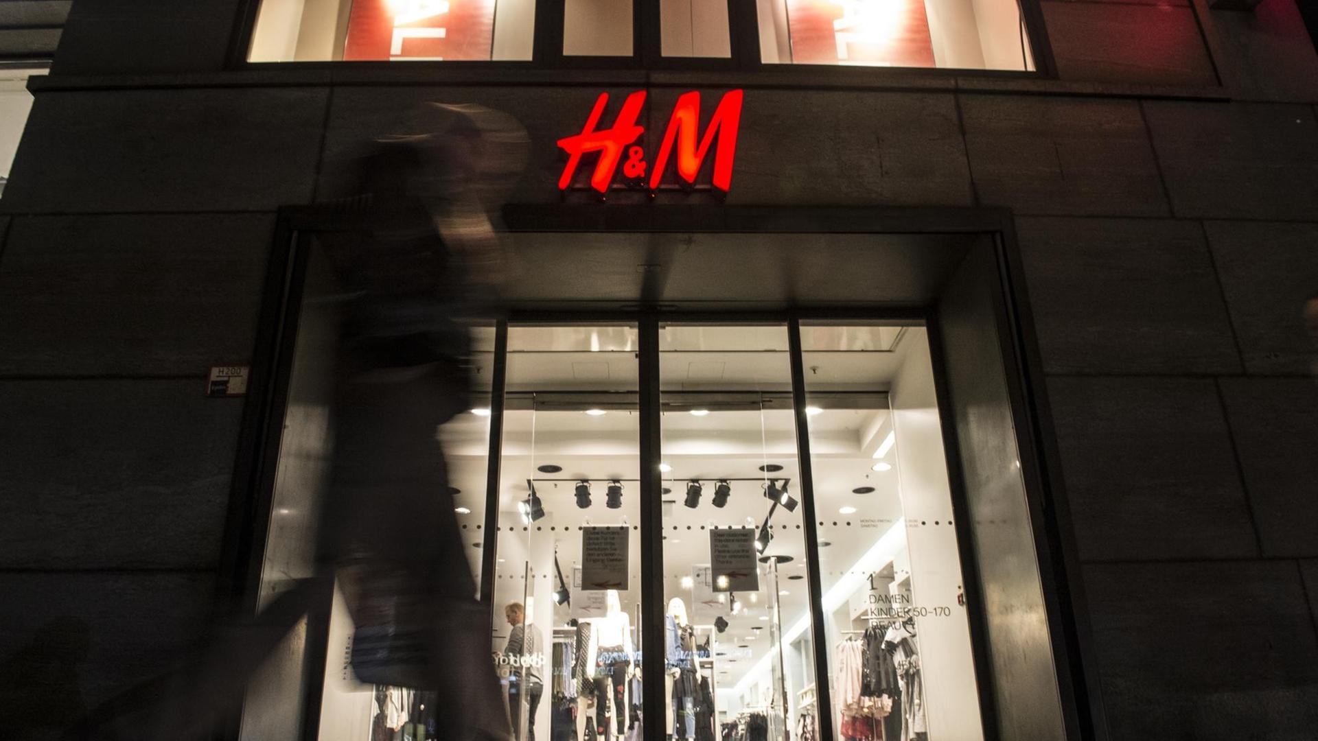 Passanten gehen am 01.02.2017 in Berlin am Abend an einer Filiale der schwedischen Modekette H&M (Hennes & Mauritz) vorbei.