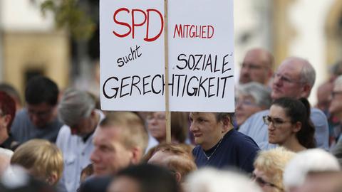 Bei einer Veranstaltung hält ein Zuschauer ein Transparent hoch: "SPD-Mitglied sucht soziale Gerechtigkeit"