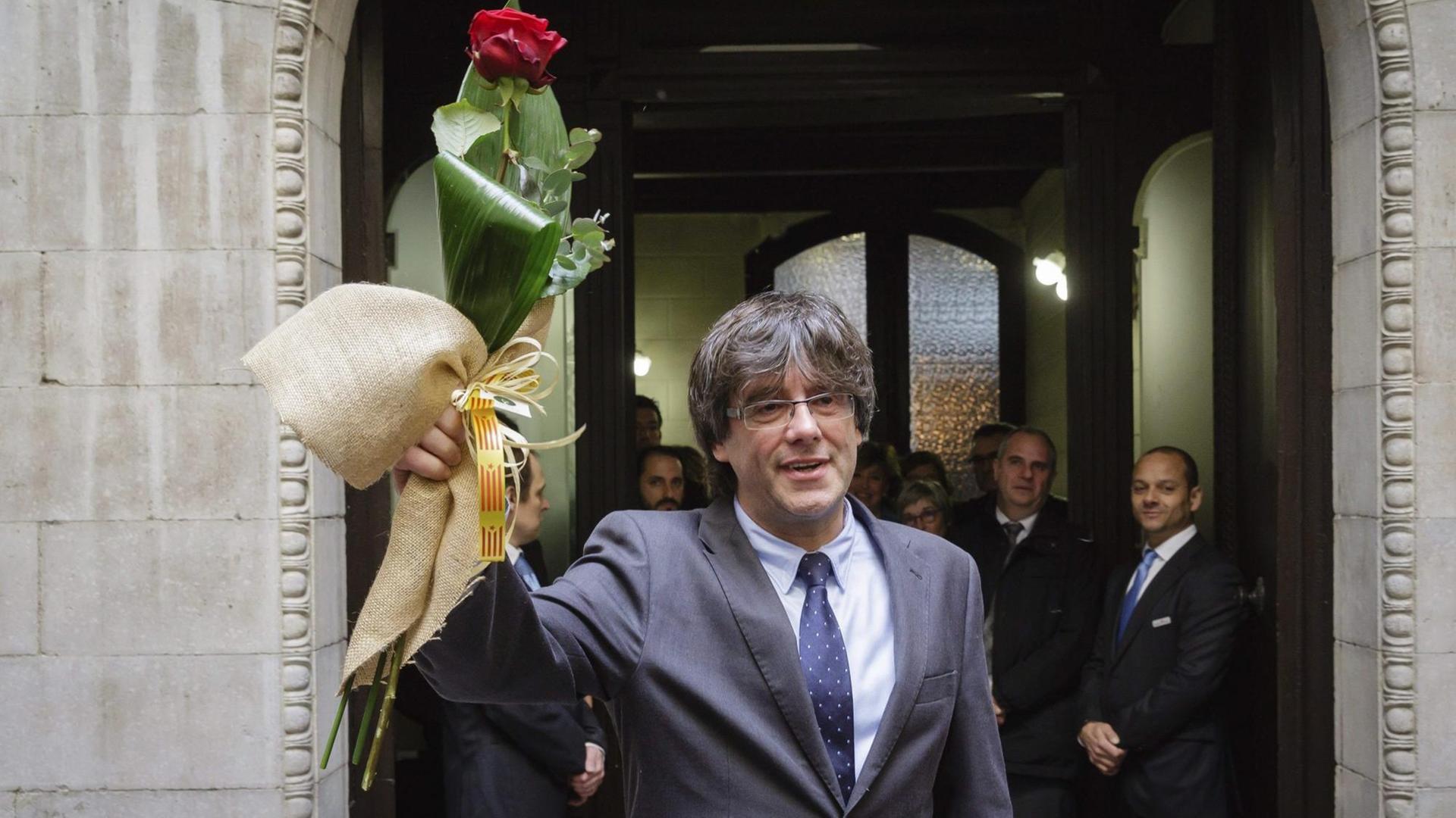 Carles Puigdemont winkt nach seiner Wahl mit einer Rose in der Hand.