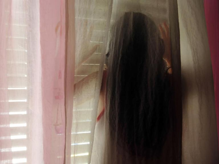 Ein Mädchen steht hinter einem Vorhang.