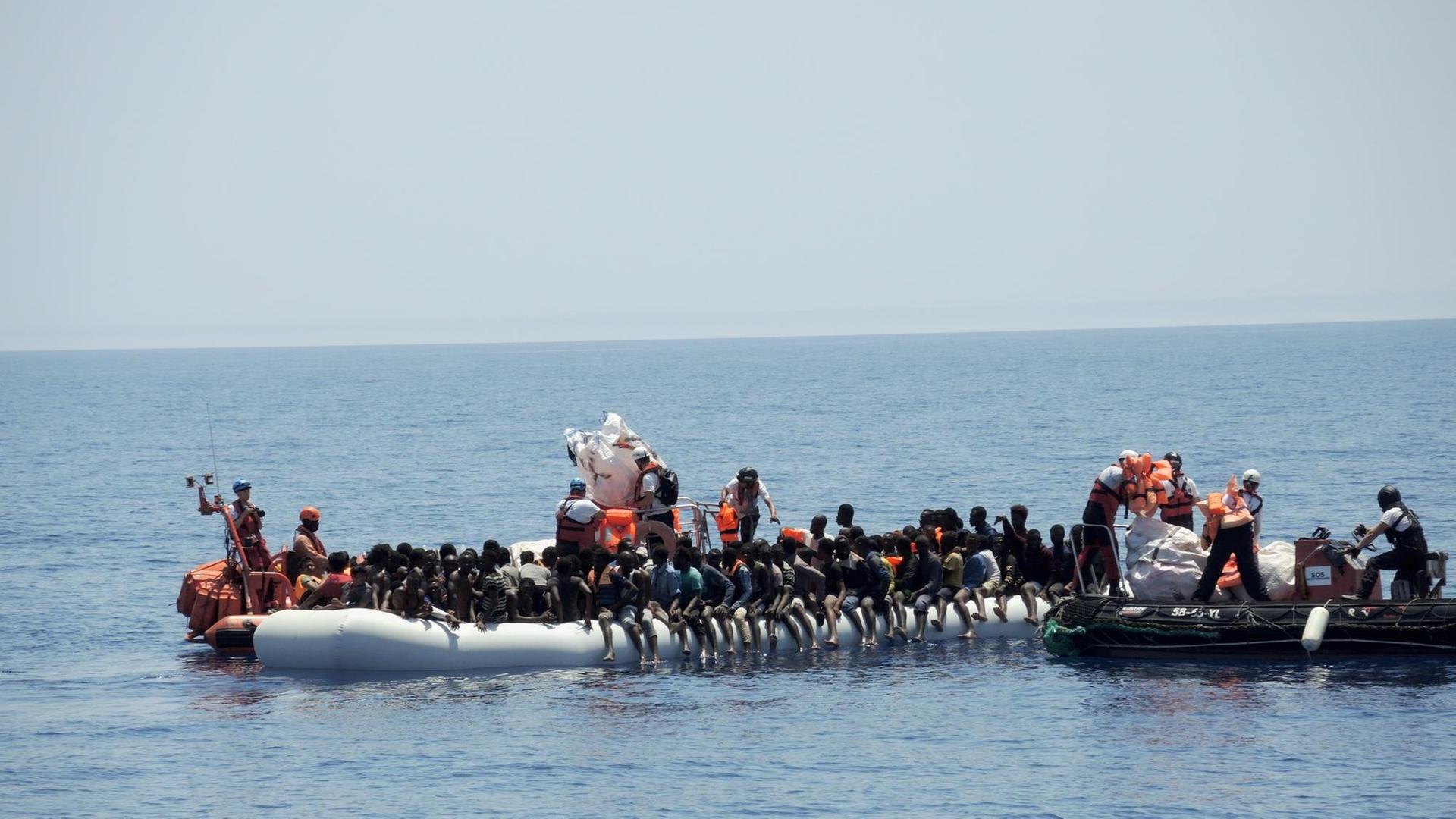Rettungskräfte der Hilfsorganisationen Ärzte ohne Grenzen und SOS Méditerranée nähern sich einem überfüllten Schlauchboot im Mittelmeer. Die Menschen wurden auf das Rettungsschiff "Aquarius" gebracht.