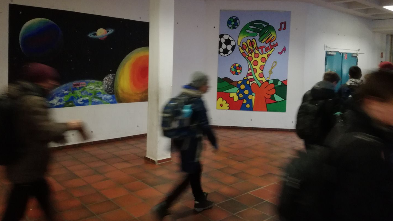 Schüler laufen an bemalten Wänden vorbei durch die Freiherr-vom-Stein-Realschule in Bonn