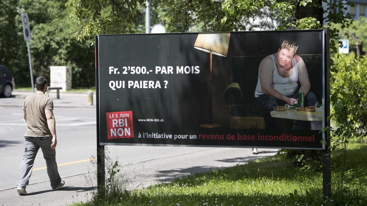 Ein Mann geht am 25.05.2016 in Genf an einem Plakat vorbei, das auf die bevorstehende Volksabstimmung in der Schweiz, im besonderen auf die Forderung nach bedingungslosem Grundeinkommen, aufmerksam macht.