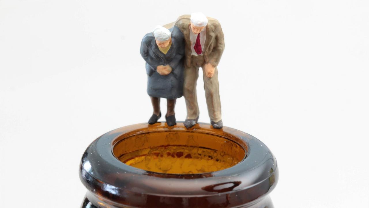 Figuren als altes Seniorenpaar steht auf dem dem Rand einer Bierflasche.