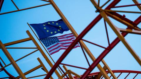 Eine EU-Fahne und eine US-Fahne wehen in Hamburg auf einer noch nicht fertig aufgebauten Achterbahn.