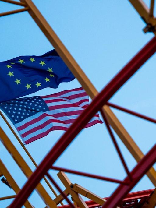 Eine EU-Fahne und eine US-Fahne wehen in Hamburg auf einer noch nicht fertig aufgebauten Achterbahn.
