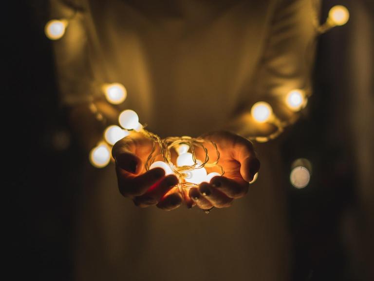 Eine Person hält die leuchtenden Lampen einer Lichterkette in den Händen.
