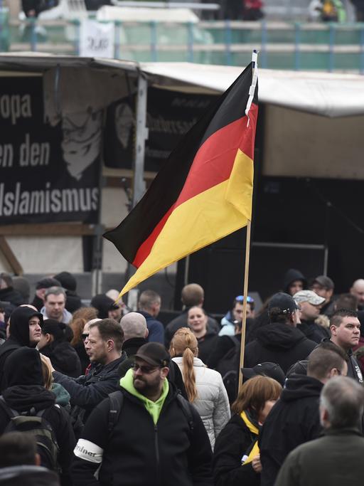 GERMANY, HANOVER : A participant holds up a German flag as far-right hooligans rally against Islamist extremism under the banner 'Hooligans against Salafism' (HoGeSa) at the former central bus station near the main train station, on November 15, 2014 in Hanover, central Germany. Around 5000 hooligans are expected to take part in the rally. AFP PHOTO / ODD ANDERSEN