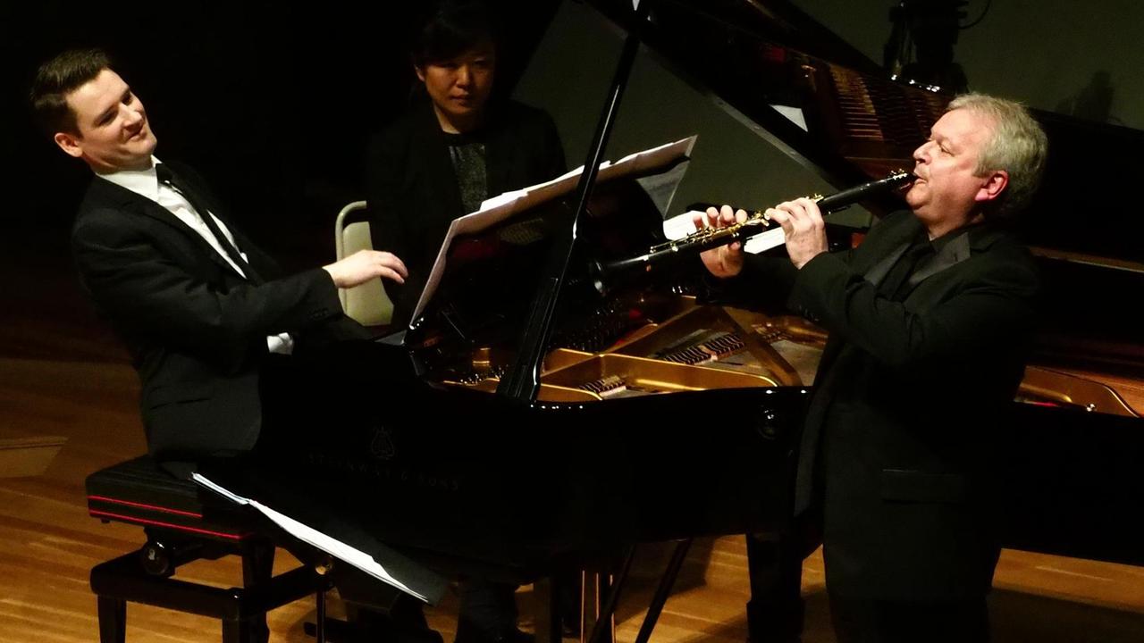Der Klarinettist Michael Collins steht neben dem geöffneten Flügel, an dem der Pianist Michael McHale spielt.
