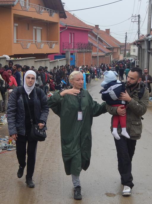 Helferin Dafina zeigt einer Flüchtlingsfamilie den Weg.