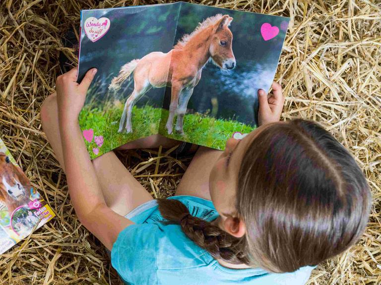 Ein Mädchen liest die Pferdezeitschrift für Kinder "Wendy" im Jahr 2016 auf einem Reiterhof