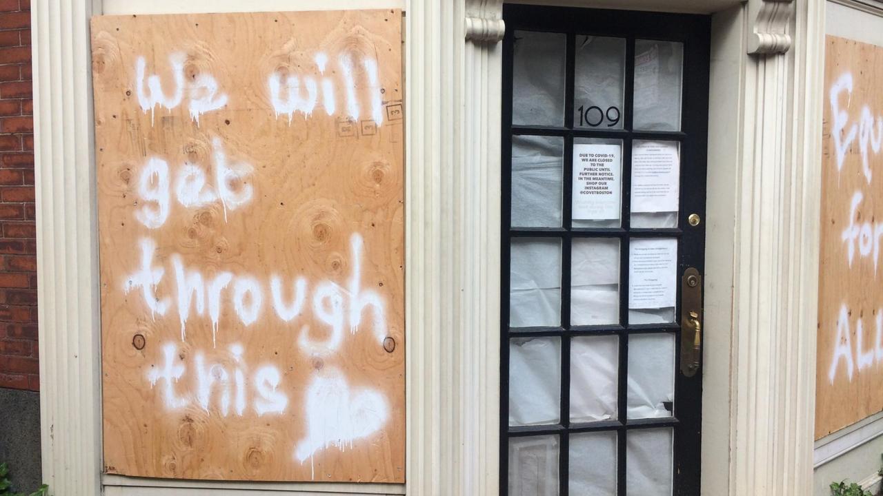 Ein Graffiti auf Pressspanplatten verkündet: "We will get through this".