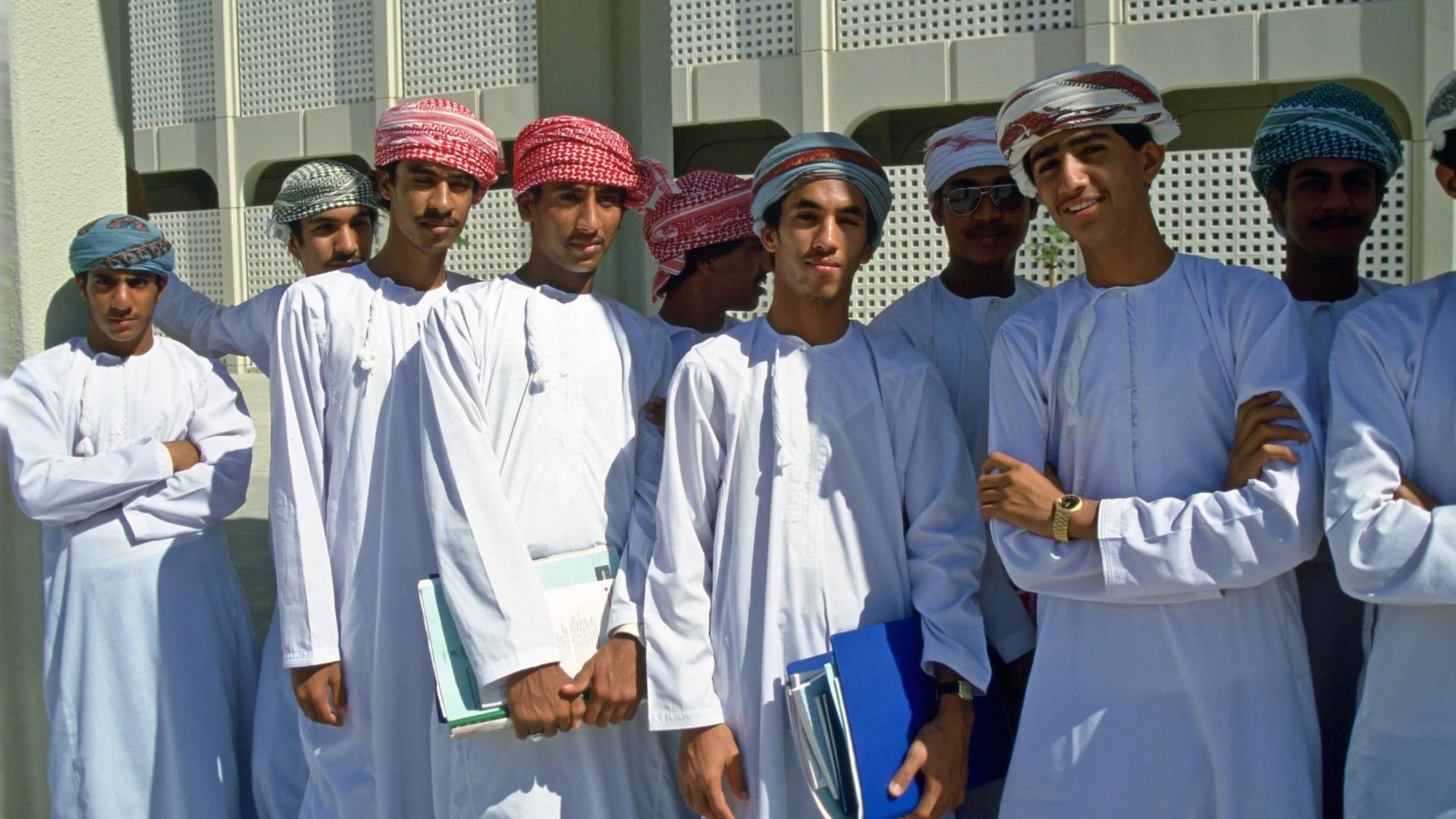 Studenten einer Universität im Oman stehen in traditioneller Kleidung vor einem Gebäude (Symbolbild)