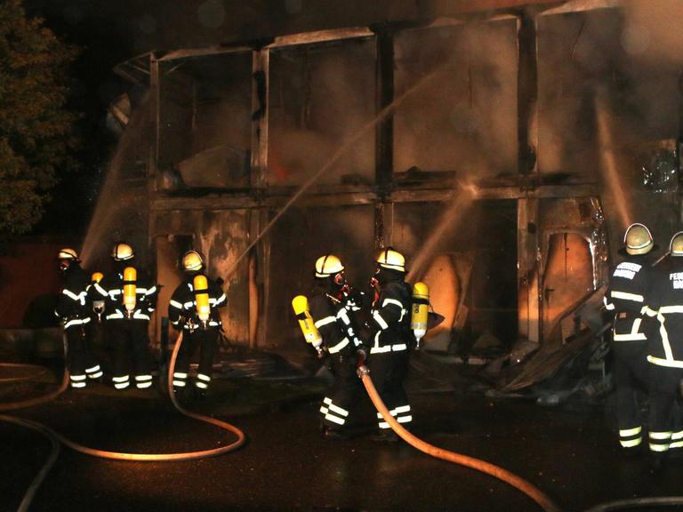 Die Feuerwehr löscht einen Brand in einem Flüchtlingslager im Stadtteil Sülldorf in Hamburg. 14 Container sind komplett ausgebrannt.
