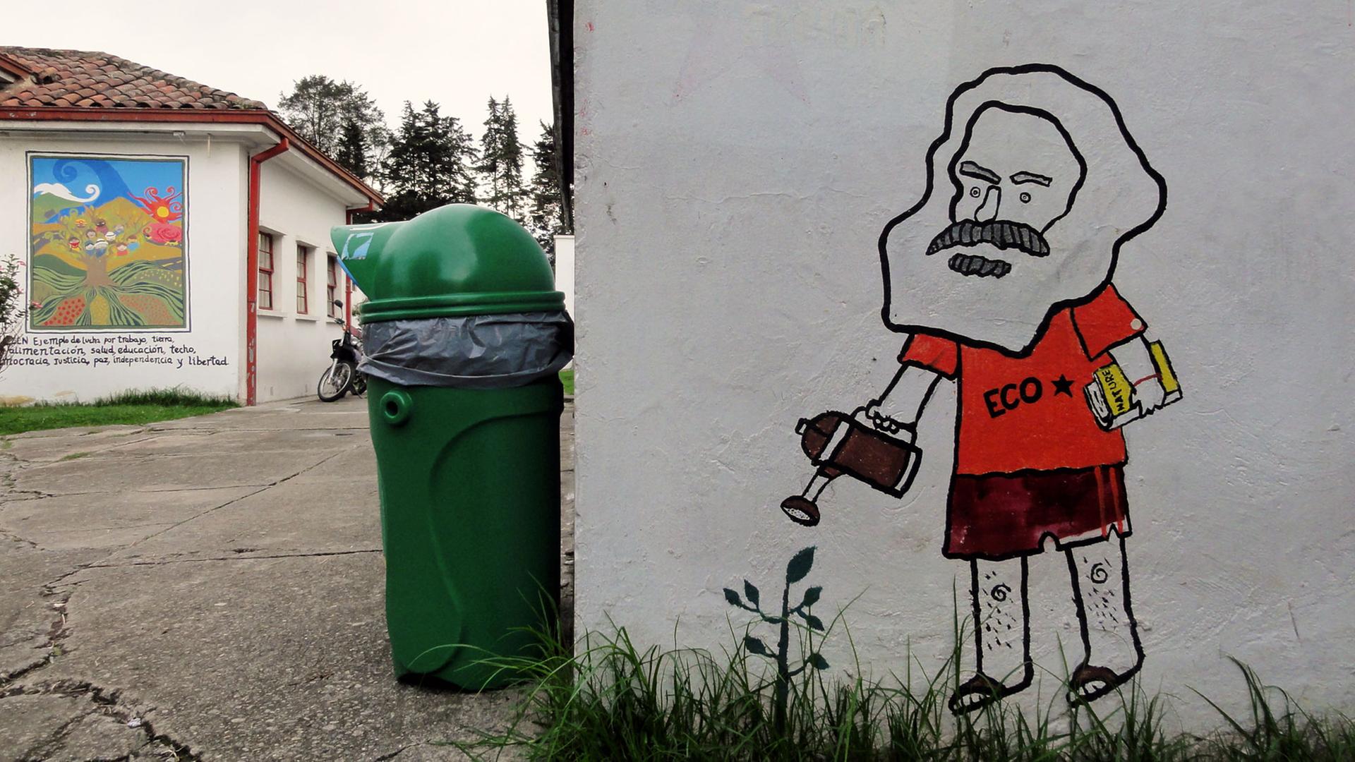 Ein Graffiti, dass eine Karikatur von Karl Marx mit Gießkanne zeigt. Die Figur trägt ein rotes T-Shirt mit dem Schriftzug "ECO" und einem schwarzen Stern darauf. 