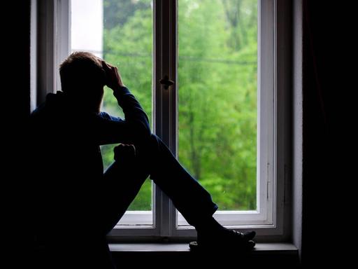 Ein Mann sitzt an einem Fenster und schaut raus