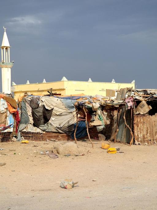 Eine Moschee mit Minarett im Hintergrund davor Hütten eines Flüchtlingslagers in Somalia.