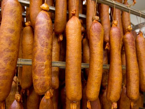 Frisch geräucherte Würste hängen in einer Fleischerei.