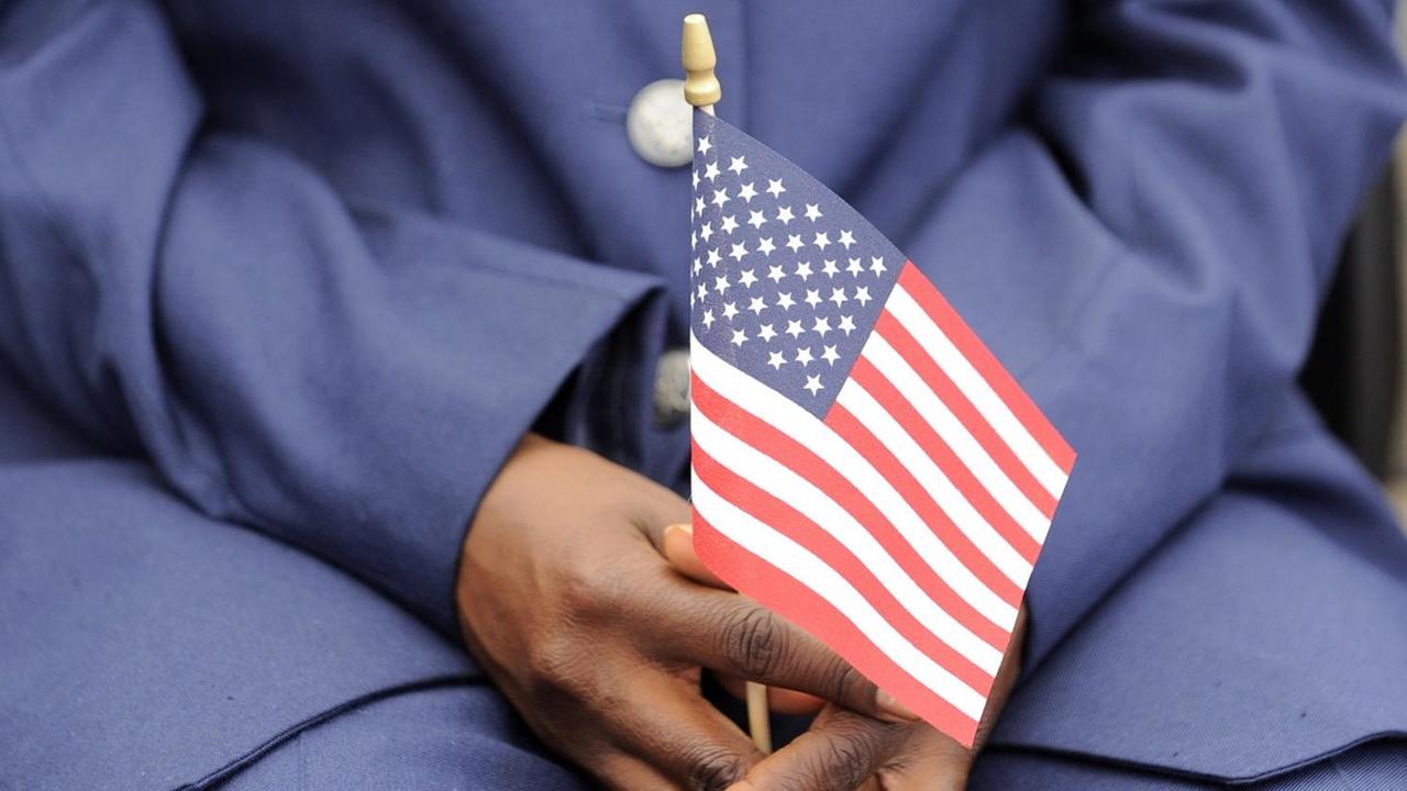 Eine Person hält eine kleine US-Flagge im Schoß.
