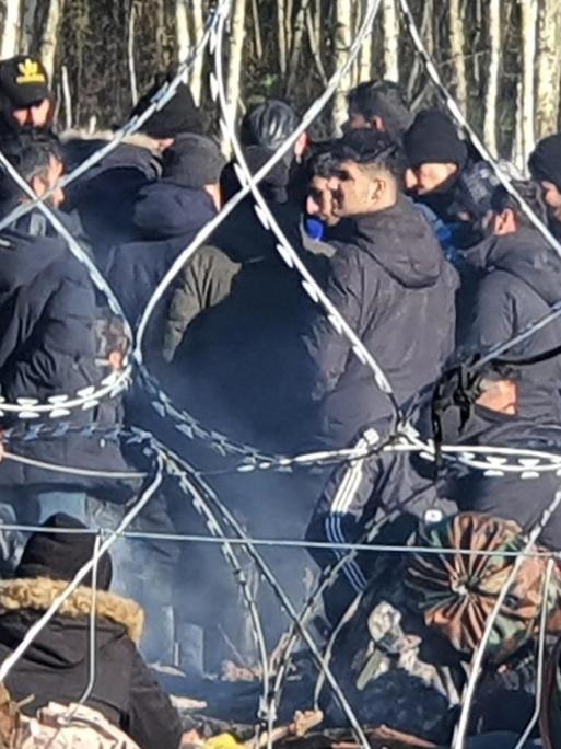 Hinter Stacheldraht ist eine Gruppe von Flüchtlingen an der polnisch-belarussischen Grenze
