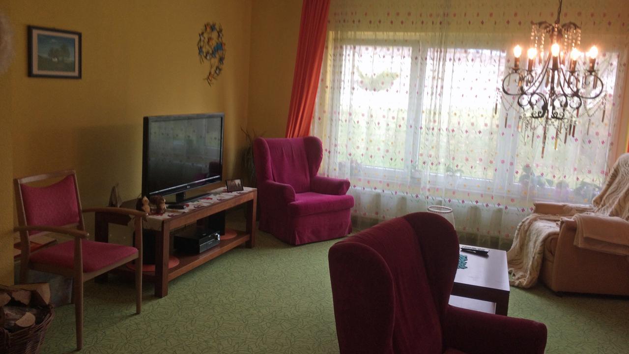 Wohnzimmer im Pflegeheim Fehlatal mit alten Sesseln, Kronleuchter und Kaminholz
