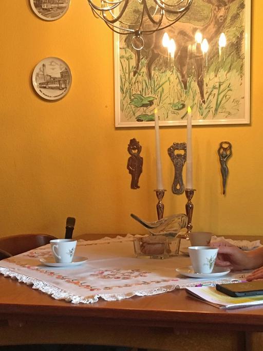 Birgit Breman sitzt mit einer Mitarbeiterin des kommunalen Pflegedienstes in ihrer Kopenhagener Wohnung vor den Kaffetassen an einem Tisch.