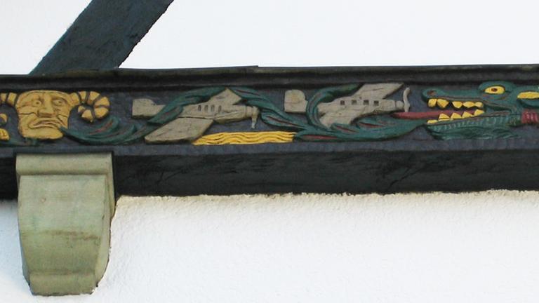 Der Balkenfries am Haus Kuhfuß zeigt unter anderem britische Jagdbomber, die von einem Drachen verfolgt werden.