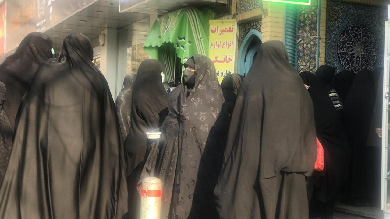 Vielen Frauen im Tschador drängen sich dicht aneinander am Eingang einer Moschee.