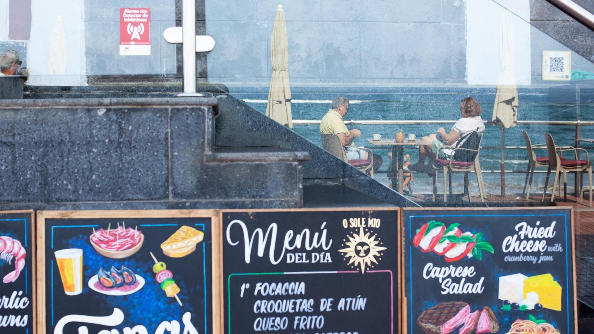 Kunden in einer Bar am Strand von Las Canteras in Gran Canaria spiegeln sich am 14.10.2020 in einem Glas.