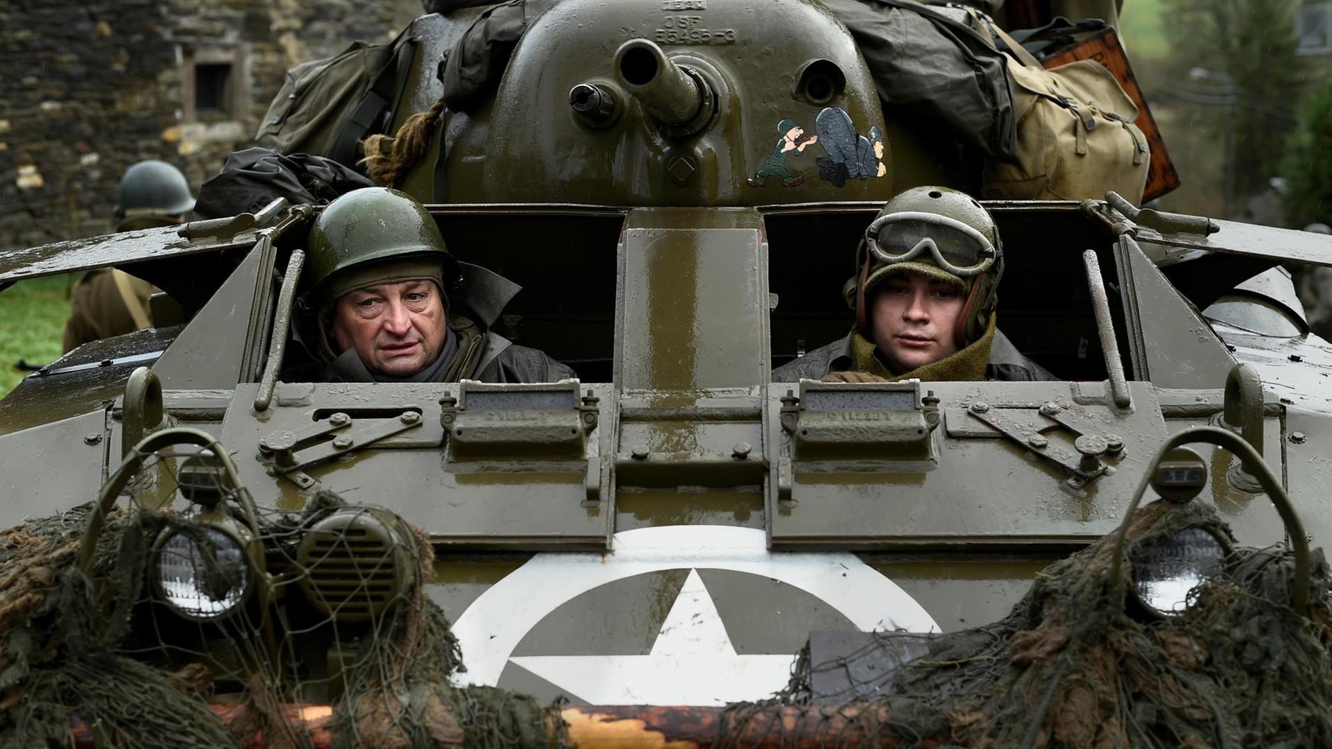Schauspieler mit Uniformen aus dem 2. Weltkrieg in einem Panzer, den die USA und Großbritannien damals benutzten.