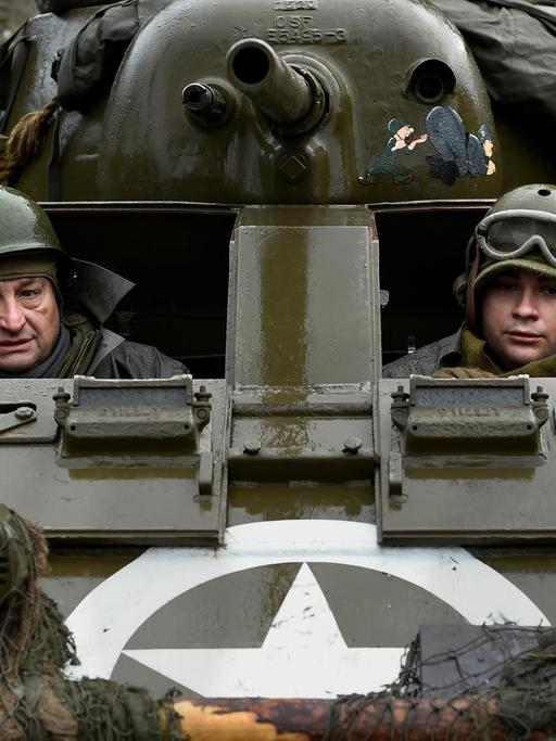 Schauspieler mit Uniformen aus dem 2. Weltkrieg in einem Panzer, den die USA und Großbritannien damals benutzten.