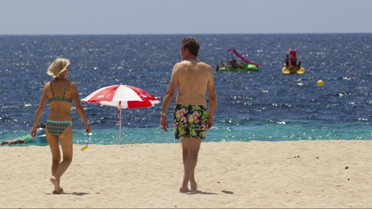 Touristen laufen am Strand auf Mallorca.