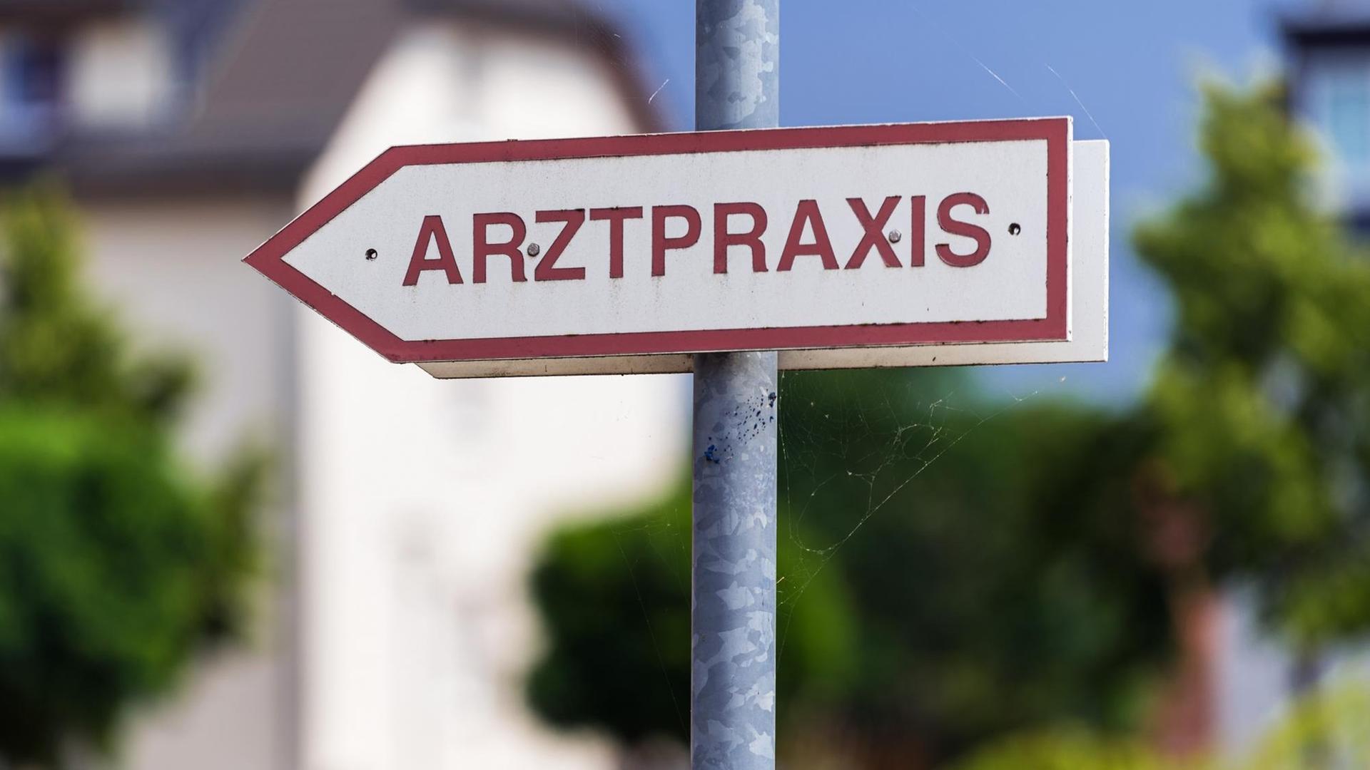 Ein Schild „Arztpraxis“ steht an der Straße.