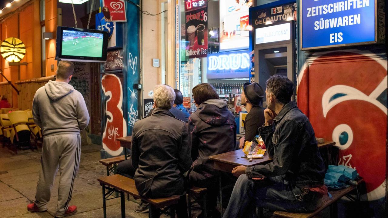 Fans schauen am 12.06.2016 beim Public Viewing vor einem Spätkauf in Berlin das Spiel der deutschen Mannschaft gegen die Ukraine bei der Fußball-EM in Frankreich auf einem Fernseher. 