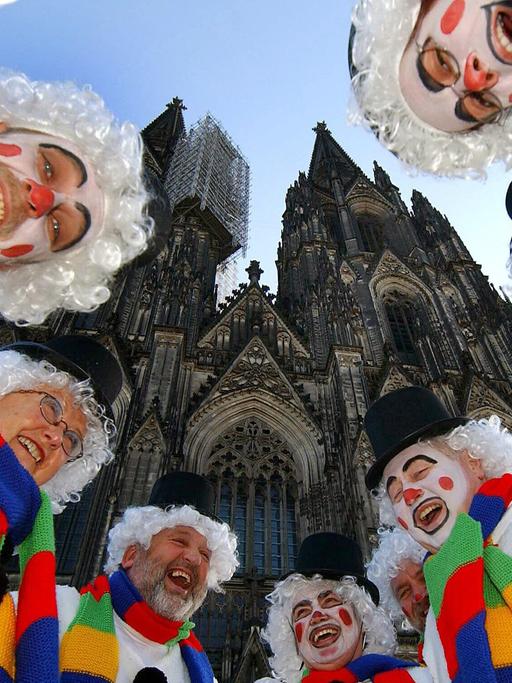 Als Schneemänner verkleidete Jecken lachen beim Karneval vor dem Dom in Köln.