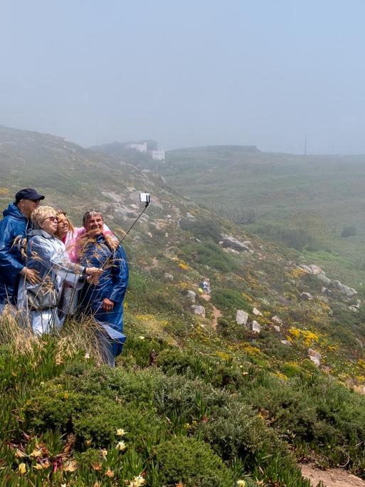 Eine Reisegruppe fotografiert sich in Portugal auf einer hügeligen grünen Wiese.
