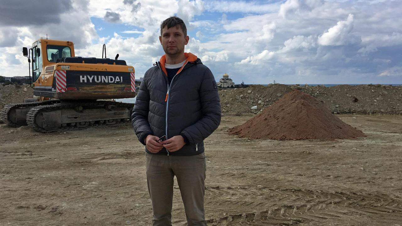 Kläger gegen das Revolutions-Denkmal Kirill Sisikow steht auf dem Beton-Fundament.