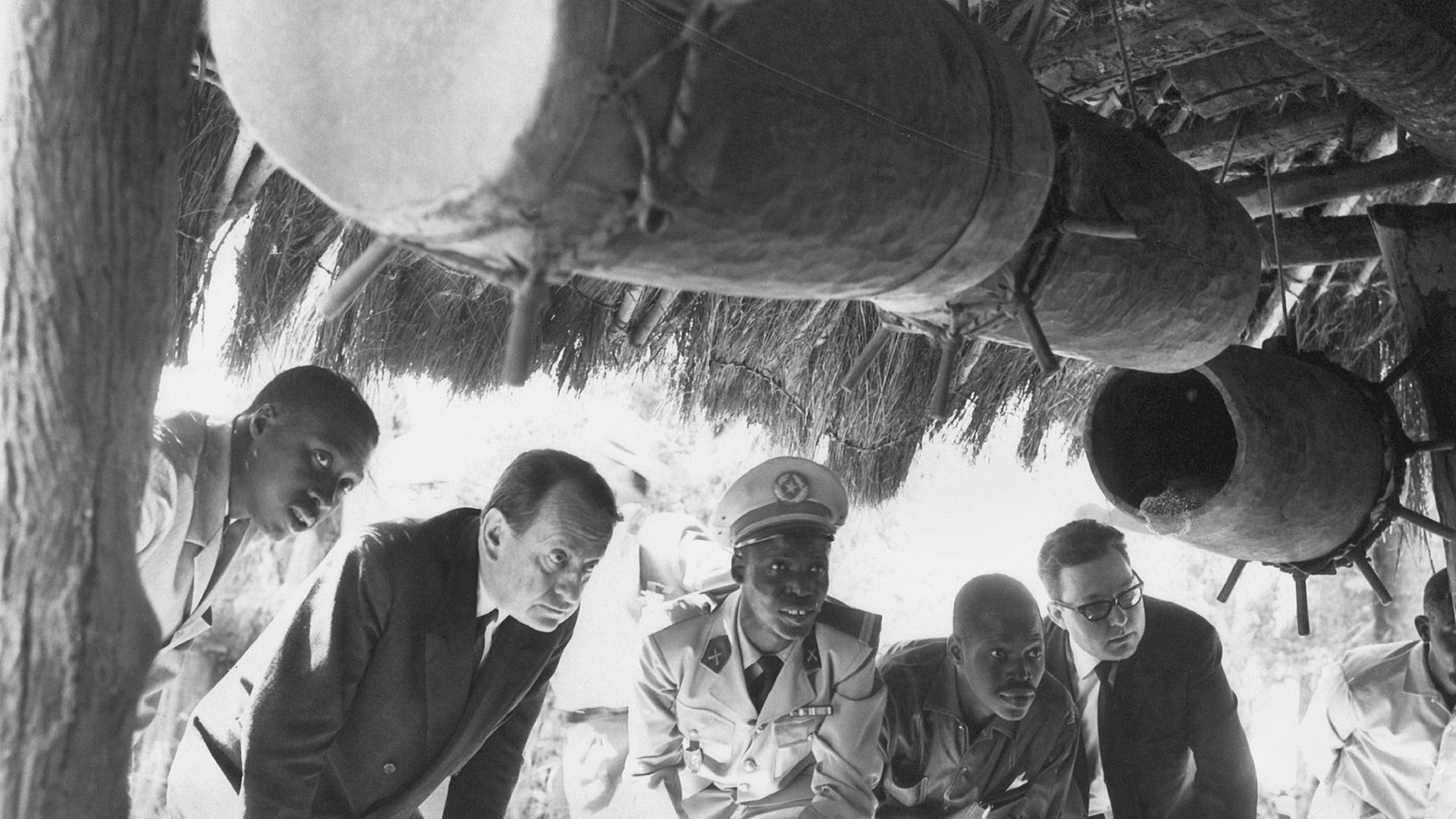 Der französische Schriftsteller und Politiker André Malraux (2.v.l.) betrachtet während eines Kunstfestivals im April 1966 in Dakar (Senegal) Trommeln.