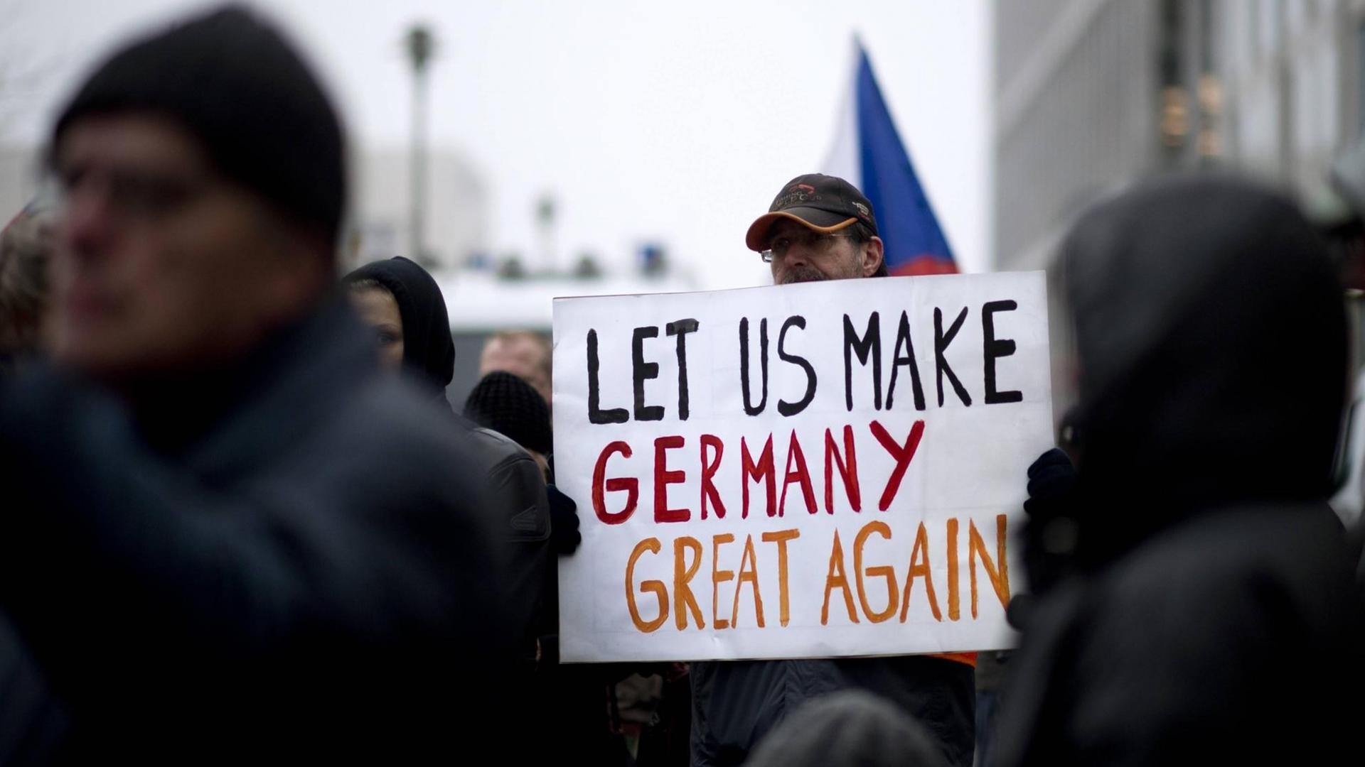 Ein Demonstrant der Bergida-Bewegung, einem Ableger von Pegida, hält ein Plakat mit der Aufschrift "Let us make Germany great again" am Hauptbahnhof im Regierungsviertel in Berlin.